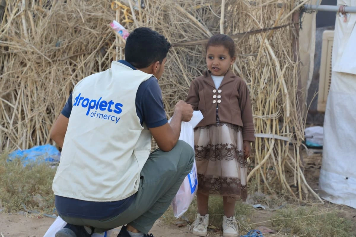 Volunteer helping a child receive aid in Yemen