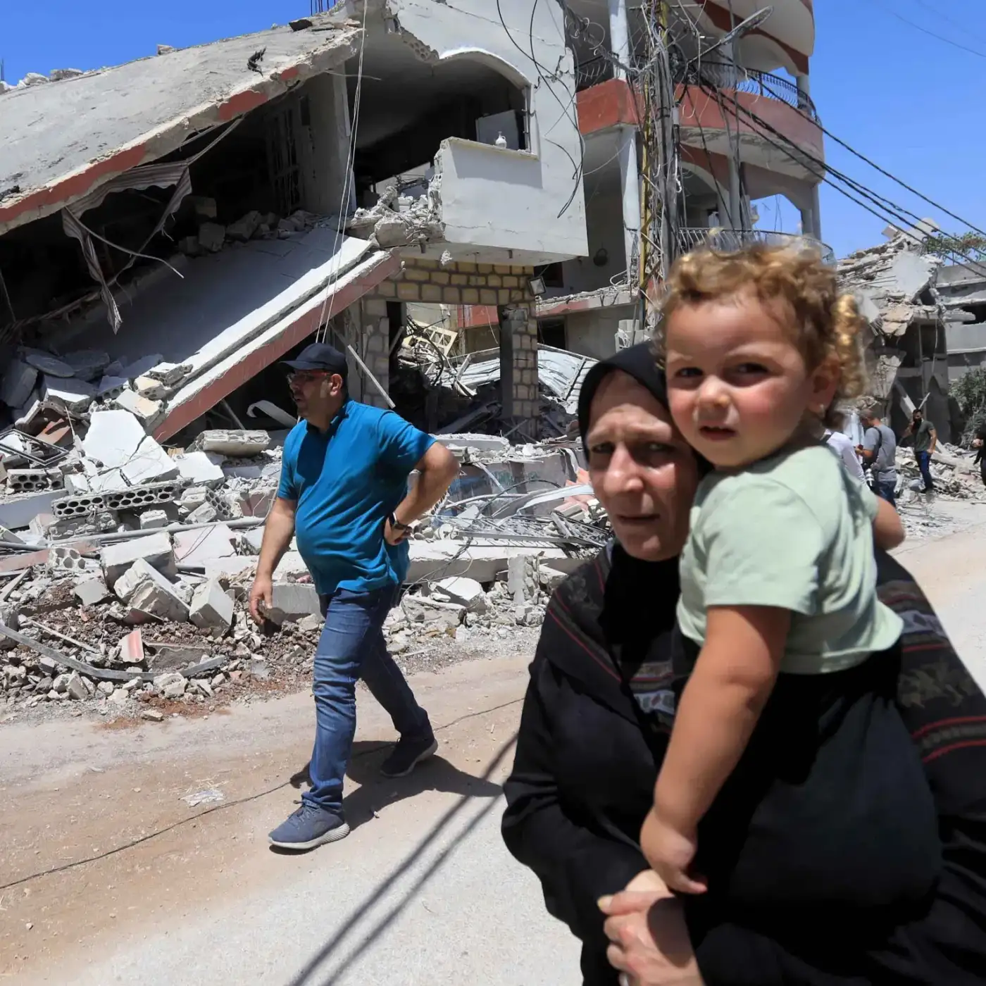 Lebanon emergency — mother carrying child through rubble